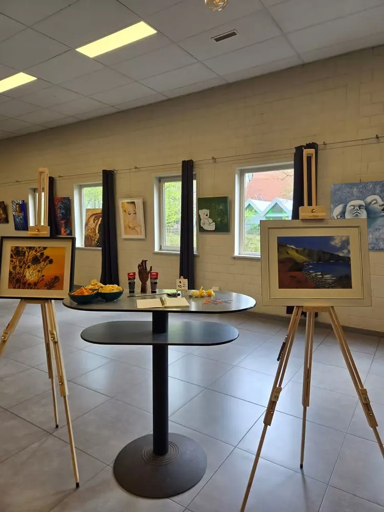Schilderijen op ezels en aan de wand tijdens een tentoonstelling in de zaal.