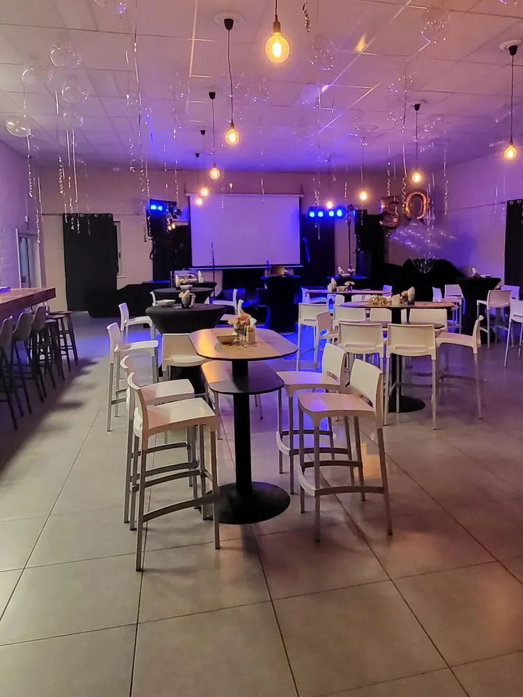 Statafels in paars en blauw licht tijdens een netwerkavond, met lampjes aan het plafond.