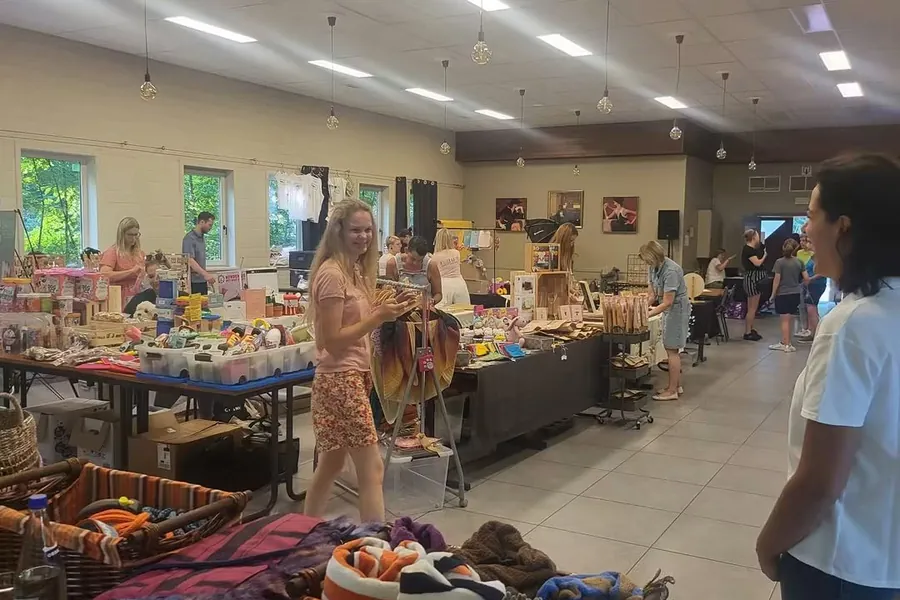 De zaal vol kraampjes met bezoekers die rondlopen tussen de stands.