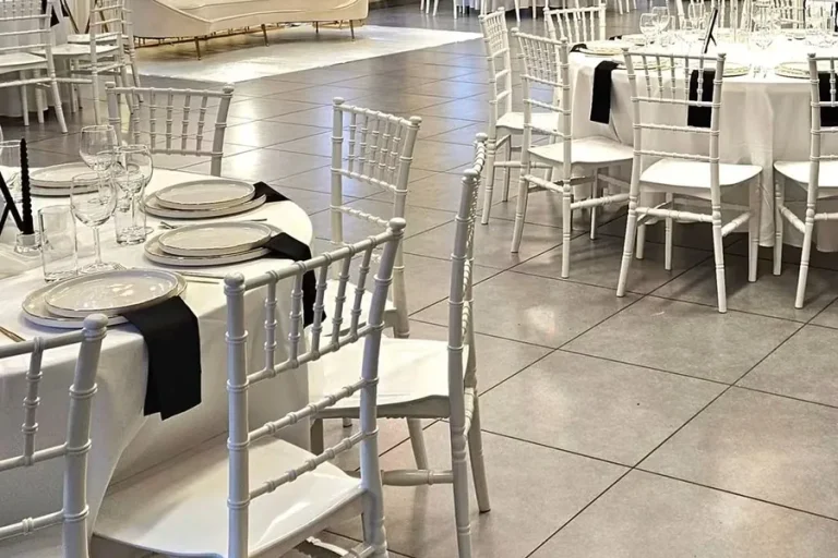 Ronde tafels met witte chiavari-stoelen en gedekt servies.
