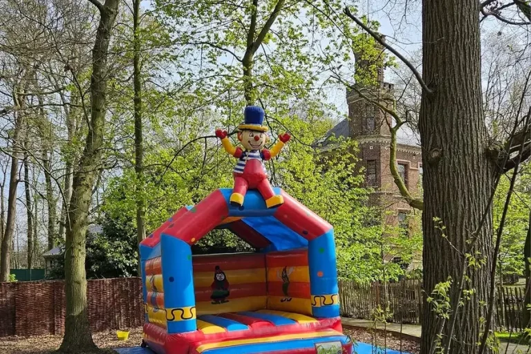 Een springkasteel tussen de bomen in het park achter de zaal.