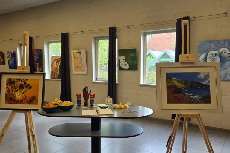 De zaal als expositieruimte, met schilderijen op ezels en statafels ertussen.