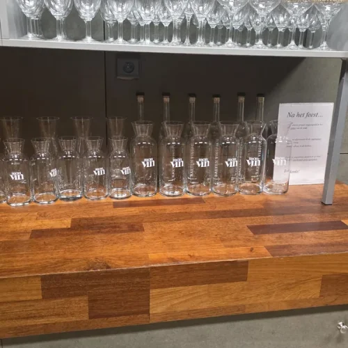 Rijen schone glazen en karaffen op de houten toog.