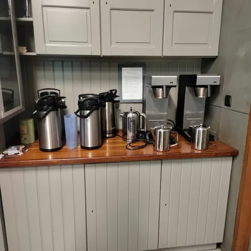 De koffiehoek met thermoskannen en koffiezetters op de houten toog.