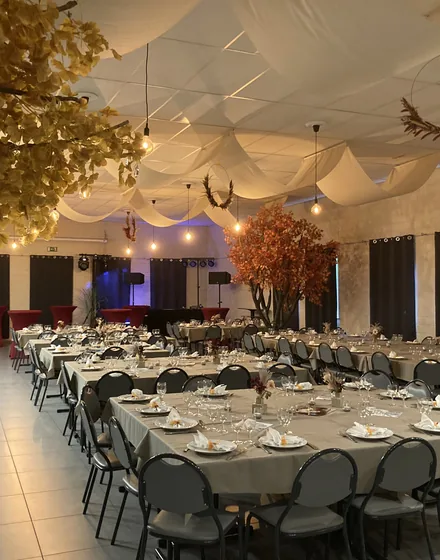 De zaal met ronde tafels en herfstdecoratie onder witte doeken.