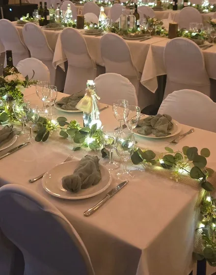 Een gedekte tafel met groendecoratie en kaarsjes.