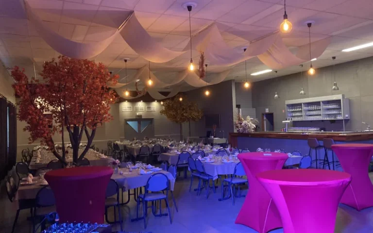 De zaal ingericht voor een bedrijfsfeest, met gedekte tafels en herfstdecoratie.
